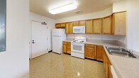 Located at 1450 Main St in Hartford, CT, this single-floor unit offers four bedrooms and two bathrooms within a practical, well-laid-out floor plan. The kitchen is equipped with warm wood cabinetry, ample counter space, and white appliances including a range, microwave, and refrigerator, set atop easy-to-clean speckled tile flooring. The entry area features built-in closet storage and a dedicated electrical panel, providing organized utility from the moment you step inside. The bedrooms are bright and comfortable, with large windows that frame views of surrounding greenery, filling each room with natural light. Flooring varies between soft carpeting and polished speckled tile. The primary bedroom is generously sized and features double closets, while additional bedrooms each include their own closet storage. The two bathrooms are clean and functional — one features a wood-toned vanity with a countertop sink and mirror, while the other includes a full tub-shower combination. Two hallways connect the spaces efficiently throughout the unit. Neutral wall tones and consistent trim work give the space a cohesive, move-in-ready appearance throughout.