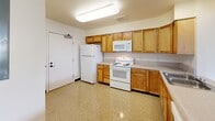 Located at 1450 Main St in Hartford, CT, this single-floor unit offers four bedrooms and two bathrooms within a practical, well-laid-out floor plan. The kitchen is equipped with warm wood cabinetry, ample counter space, and white appliances including a range, microwave, and refrigerator, set atop easy-to-clean speckled tile flooring. The entry area features built-in closet storage and a dedicated electrical panel, providing organized utility from the moment you step inside. The bedrooms are bright and comfortable, with large windows that frame views of surrounding greenery, filling each room with natural light. Flooring varies between soft carpeting and polished speckled tile. The primary bedroom is generously sized and features double closets, while additional bedrooms each include their own closet storage. The two bathrooms are clean and functional — one features a wood-toned vanity with a countertop sink and mirror, while the other includes a full tub-shower combination. Two hallways connect the spaces efficiently throughout the unit. Neutral wall tones and consistent trim work give the space a cohesive, move-in-ready appearance throughout.