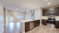 This thoughtfully designed single-floor residence offers a clean, contemporary aesthetic highlighted by light wood-look flooring, neutral warm-toned walls, and crisp white trim throughout. The open-concept kitchen serves as the heart of the home, featuring dark espresso cabinetry, quartz countertops, a large center island with an undermount sink, stainless steel appliances including a refrigerator, range, microwave, and dishwasher, and stylish pendant lighting overhead. The kitchen flows seamlessly into a bright living area filled with natural light from large windows fitted with roller shades. The bedrooms are generously proportioned, each offering ample room and easy access to natural light through well-placed windows. One bedroom includes direct access to an en suite bathroom, which impresses with a double-sink vanity topped with a white quartz countertop, dark cabinetry, backlit mirrors, and a sleek glass-enclosed walk-in shower. A second full bathroom provides a bathtub with shower combination and a single-sink dark wood vanity. Additional highlights include a spacious walk-in closet equipped with wrap-around shelving and a hanging rod system, recessed lighting, and panel-style interior doors that complete the modern look throughout the unit.