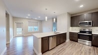 This thoughtfully designed single-floor residence offers a clean, contemporary aesthetic highlighted by light wood-look flooring, neutral warm-toned walls, and crisp white trim throughout. The open-concept kitchen serves as the heart of the home, featuring dark espresso cabinetry, quartz countertops, a large center island with an undermount sink, stainless steel appliances including a refrigerator, range, microwave, and dishwasher, and stylish pendant lighting overhead. The kitchen flows seamlessly into a bright living area filled with natural light from large windows fitted with roller shades. The bedrooms are generously proportioned, each offering ample room and easy access to natural light through well-placed windows. One bedroom includes direct access to an en suite bathroom, which impresses with a double-sink vanity topped with a white quartz countertop, dark cabinetry, backlit mirrors, and a sleek glass-enclosed walk-in shower. A second full bathroom provides a bathtub with shower combination and a single-sink dark wood vanity. Additional highlights include a spacious walk-in closet equipped with wrap-around shelving and a hanging rod system, recessed lighting, and panel-style interior doors that complete the modern look throughout the unit.