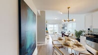 This single-floor residence offers a thoughtfully designed open-concept layout that seamlessly connects the living, dining, and kitchen areas. Light-toned hardwood flooring flows throughout the main living spaces, complementing the bright, white walls and creating a clean, contemporary aesthetic.

The kitchen is appointed with tall white shaker cabinetry, dark granite countertops, a reflective tile backsplash, and stainless steel appliances, including a refrigerator, range, microwave, and dishwasher. Adjacent to the kitchen, the dining area is anchored by a striking brass and glass globe chandelier, with space for a full dining table.

The living room benefits from generous natural light through large windows and a sliding glass door that opens to a balcony, offering open outdoor views. Two bedrooms feature light-filtering windows with blinds and drapery, and light wood-toned flooring. One bedroom includes built-in wall shelving flanking a large flat-screen TV.

Two bathrooms serve the unit: one with a tiled walk-in shower and dark granite vanity, and another with a full soaking tub and tiled surround. Both feature neutral tile work and clean, minimal finishes throughout.