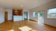 This thoughtfully designed single-floor residence offers a clean, modern aesthetic throughout. The open-concept living and dining area is bathed in natural light from large windows and a sliding glass door that leads to a private balcony overlooking lush, mature trees. Warm honey-toned hardwood flooring flows seamlessly across the main living spaces, complemented by crisp white walls and recessed lighting.

The kitchen is well-appointed with warm wood cabinetry, white countertops, and a full suite of stainless steel appliances including a refrigerator, range, over-the-range microwave, and dishwasher. A peninsula counter separates the kitchen from the living area, providing both additional workspace and a natural visual boundary.

The bedrooms are carpeted for comfort, each featuring large sliding windows that frame serene outdoor views of trees and open sky. One bedroom includes a closet with built-in shelving. A hallway lined with wood-trimmed doors connects the private areas of the unit.

The bathroom features tile flooring, warm wood cabinetry with a white countertop vanity, a wall-mounted mirror, and a full-size soaking tub with a tub/shower combination. Clean lines and neutral finishes throughout create a cohesive, move-in ready space.