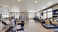 Located at 121 E Victory Rd in Meridian, Idaho, this fitness center offers a comprehensive workout environment designed to accommodate a broad range of exercise needs. The single-floor facility is generously proportioned, providing ample room for members to move freely between equipment zones without feeling crowded.

The strength training area is well-stocked with a variety of Hoist selectorized machines targeting multiple muscle groups, along with a dedicated dumbbell rack and mirrored walls that enhance the sense of space and allow users to monitor their form. Adjacent to the strength section, the cardio zone features multiple treadmills, ellipticals, stationary bikes—including a spin-style cycle—and a rowing machine, catering to diverse cardiovascular preferences. Wall-mounted flat-screen televisions are positioned throughout for entertainment during workouts.

Natural light fills the space through rows of windows fitted with roller shades, complemented by recessed ceiling lighting and ceiling fans that promote air circulation. The flooring consists of durable, light-toned carpet throughout. A designated area near the entrance houses stability balls, resistance accessories, and a water station, rounding out the facility's functional offerings. The overall ambiance is clean, bright, and purposefully organized.