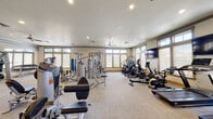 Located at 121 E Victory Rd in Meridian, Idaho, this fitness center offers a comprehensive workout environment designed to accommodate a broad range of exercise needs. The single-floor facility is generously proportioned, providing ample room for members to move freely between equipment zones without feeling crowded.

The strength training area is well-stocked with a variety of Hoist selectorized machines targeting multiple muscle groups, along with a dedicated dumbbell rack and mirrored walls that enhance the sense of space and allow users to monitor their form. Adjacent to the strength section, the cardio zone features multiple treadmills, ellipticals, stationary bikes—including a spin-style cycle—and a rowing machine, catering to diverse cardiovascular preferences. Wall-mounted flat-screen televisions are positioned throughout for entertainment during workouts.

Natural light fills the space through rows of windows fitted with roller shades, complemented by recessed ceiling lighting and ceiling fans that promote air circulation. The flooring consists of durable, light-toned carpet throughout. A designated area near the entrance houses stability balls, resistance accessories, and a water station, rounding out the facility's functional offerings. The overall ambiance is clean, bright, and purposefully organized.