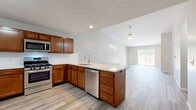 Located at 1610 Franklin Ave in Salem, Ohio, this single-story home offers a well-designed open-concept layout that seamlessly connects the kitchen and living area. The kitchen is a standout feature, equipped with warm-toned wood cabinetry, light quartz countertops, and stainless steel appliances including a gas range, over-the-range microwave, and dishwasher. A peninsula with additional cabinetry and a built-in sink provides extra prep space and a natural division between the kitchen and the expansive living area. Light-tone wood-style flooring runs throughout the main living spaces, contributing to a clean and cohesive aesthetic.

The living area benefits from a ceiling fan, recessed lighting, and a sliding glass door that allows natural light to flow in. Bedrooms feature plush carpeting, ceiling fans, and windows with outdoor views, along with closets fitted with wire shelving for practical storage. The bathroom includes a wood-vanity with a quartz countertop, undermount sink, and a tub-shower combination. A dedicated utility room houses the water heater and HVAC equipment. Textured ceilings are found throughout, adding a consistent finish to the home.