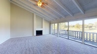 Located in Overland Park, Kansas, this single-floor unit at Club at IC offers a well-designed layout with a variety of functional spaces. The living room is a standout feature, showcasing distinctive exposed beam ceilings with textured paneling, plush wall-to-wall carpeting, and a ceiling fan. A classic fireplace anchors one wall, while a full wall of sliding glass doors floods the room with natural light and provides direct access to a private balcony overlooking lush, tree-lined green space. The kitchen is equipped with white shaker-style cabinetry, grey laminate countertops, tile backsplash, and black appliances including a gas range, refrigerator, and dishwasher, complemented by a double stainless steel sink and wood-look flooring. The bedrooms are carpeted and offer neutral tones with ample wall space; at least one bedroom includes a walk-in closet. A full bathroom features a vanity with grey tile surround, a tub-shower combination with white tile surround, and wood-look vinyl flooring. The entryway provides a clean transition into the main living areas, completing this comfortable and functional residential unit.