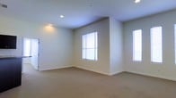 This single-floor space offers a bright and open layout designed with simplicity and functionality in mind. The interior is finished with neutral, warm-toned walls that create a calm and inviting atmosphere throughout. Soft wall-to-wall carpeting covers the floors, adding a sense of comfort underfoot and contributing to the overall understated aesthetic. Recessed ceiling lights provide even, ambient illumination, complementing the generous natural light that streams in through multiple large windows fitted with light-filtering blinds. The windows are positioned to maximize daylight from multiple angles, keeping the space feeling airy and well-lit throughout the day. Clean white baseboards frame the perimeter of the room, adding a crisp finishing detail against the neutral walls. The layout is open and unobstructed, offering flexible potential for various uses and configurations. The overall design is modern and minimal, with a straightforward floor plan that emphasizes usability and ease of movement. The combination of natural light, soft carpeting, and neutral finishes gives the space a welcoming and versatile character well-suited to a variety of purposes.