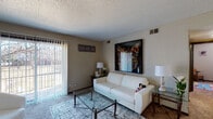 Located at 2768 S Seneca St in Wichita, Kansas, this single-floor unit offers a practical and comfortable layout spread across several distinct rooms. The living room serves as the central gathering space, featuring neutral-toned carpet, a textured ceiling, and a large sliding glass door fitted with vertical blinds that floods the room with natural light and provides direct access to an outdoor patio area. The entryway opens into this same living space, offering room for additional seating or display furniture.

The kitchen is equipped with dark cabinetry providing ample upper and lower storage, light countertops, a double-basin sink, a dishwasher, and tile flooring, giving it a clean and functional character. A dedicated dining area is situated nearby, adding to the unit's practical flow.

The primary bedroom is generously proportioned with carpet flooring, a closet, and a window that brings in natural light. Additional bedrooms also feature carpet, windows with blinds, and sufficient space for furnishings. The bathroom includes wood-look flooring, a vanity with dark cabinetry, a toilet, and a shower-tub combination. Textured ceilings are consistent throughout the unit, contributing to its cohesive interior character.