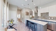Located at 123 Merritt St in Fort Worth, TX, this thoughtfully designed one-bedroom, one-bathroom residence offers a modern aesthetic with high-quality finishes throughout. The open-concept living, dining, and kitchen area serves as the heart of the home, creating a seamless flow ideal for both everyday living and entertaining. The kitchen is a standout feature, showcasing two-tone cabinetry with wood-grain lower cabinets and crisp white uppers, a mosaic tile backsplash, stainless steel appliances including a full-size refrigerator and dishwasher, a stainless range hood, and a large center island with a quartz countertop and bar seating for two. Pendant lighting above the island adds a refined touch, while light wood-look flooring extends throughout the living areas. The bedroom is a calm, light-filled retreat with a window overlooking the exterior, soft neutral walls, and a built-in wood-grain wardrobe for ample storage. The bathroom is finished in large-format porcelain tile and features a soaking tub with an overhead rain showerhead, a floating vanity with undermount sink, and clean chrome fixtures. A dedicated laundry area completes this efficiently designed home.