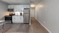 Located at 270 Laurel St in Hartford, Connecticut, this single-floor studio unit offers a thoughtfully designed open layout that seamlessly integrates the living, sleeping, and kitchen areas into one cohesive space. Durable wood-look flooring runs throughout, complemented by neutral gray walls and clean white trim that give the interior a bright, modern aesthetic.

The main living and sleeping area is generously proportioned, featuring a large window fitted with vertical blinds that allows natural light to fill the room. A contemporary globe pendant light fixture adds a stylish focal point overhead, while a compact seating area with a tufted gray sofa provides a comfortable lounge space. A sleek bar-height desk and stool set offers a dedicated workspace within the room.

The kitchen is efficiently laid out with crisp white shaker-style cabinetry, a subway tile backsplash, stainless steel appliances including a full-size refrigerator and microwave, and an under-cabinet sink — delivering full functionality in a compact footprint. A short entry hall connects the main space to the front door, adding a sense of arrival and privacy.

The bathroom is finished in an all-white palette with tile walls, a vanity with cabinet storage, a mirrored medicine cabinet with overhead lighting, and a tub-shower combination — clean, practical, and well-appointed throughout.