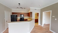 Located at 701 Leora Ln in Lewisville, TX, this single-floor residence offers a well-designed layout with a cohesive blend of modern finishes and functional living spaces. The entryway welcomes you with light-toned hardwood-style flooring and crown molding that carries throughout the main living areas, establishing a clean and polished aesthetic.

The open-concept kitchen is a standout feature, equipped with rich dark wood cabinetry, light-toned countertops, and a full suite of black appliances including a refrigerator, range, built-in microwave, and a stainless steel sink. A wraparound breakfast bar peninsula provides additional prep and dining space, while track lighting overhead ensures excellent illumination. The kitchen flows naturally into the surrounding living areas.

The living room is generously sized and bathed in natural light from multiple windows fitted with horizontal blinds. A ceiling fan adds both comfort and a finishing touch to the space. A door from the living area provides direct access to the outdoors.

The bedroom continues the warm, neutral palette with hardwood-style flooring, a ceiling fan with light fixture, and a large window that invites natural light. The bathroom is well-appointed with dark wood vanity cabinetry, a wide mirror, light countertops, tile flooring, and a full soaking tub and shower combination with additional overhead wall-mounted cabinetry for storage.