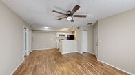 Located at 3440 N Goldenrod Rd in Winter Park, Florida, this single-story, one-bedroom, one-bathroom unit offers a well-organized layout across its single floor. Wood-look flooring runs consistently throughout the space, lending a clean and cohesive aesthetic to every room.

The open-concept living and kitchen area forms the heart of the unit. The living room is bathed in natural light from a sliding glass door that opens directly onto the private patio, offering views of surrounding greenery. A ceiling fan with a light fixture overhead adds both style and comfort. A second sliding glass door provides additional access to the patio from another angle.

The kitchen is positioned adjacent to the living space and features white cabinetry, light countertops, a stainless steel sink, and black appliances including a refrigerator, range, and dishwasher. A peninsula counter separates the kitchen from the living area, creating a natural transition between the two spaces.

The bedroom is a comfortable, well-proportioned room with a window allowing natural light and a dedicated closet for storage. It also includes sliding door access to a secondary patio area. The bathroom includes a vanity with white cabinetry, a full tub and shower combination, and consistent wood-look flooring. A separate closet provides additional storage within the unit.