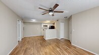 Located at 3440 N Goldenrod Rd in Winter Park, Florida, this single-story, one-bedroom, one-bathroom unit offers a well-organized layout across its single floor. Wood-look flooring runs consistently throughout the space, lending a clean and cohesive aesthetic to every room.

The open-concept living and kitchen area forms the heart of the unit. The living room is bathed in natural light from a sliding glass door that opens directly onto the private patio, offering views of surrounding greenery. A ceiling fan with a light fixture overhead adds both style and comfort. A second sliding glass door provides additional access to the patio from another angle.

The kitchen is positioned adjacent to the living space and features white cabinetry, light countertops, a stainless steel sink, and black appliances including a refrigerator, range, and dishwasher. A peninsula counter separates the kitchen from the living area, creating a natural transition between the two spaces.

The bedroom is a comfortable, well-proportioned room with a window allowing natural light and a dedicated closet for storage. It also includes sliding door access to a secondary patio area. The bathroom includes a vanity with white cabinetry, a full tub and shower combination, and consistent wood-look flooring. A separate closet provides additional storage within the unit.