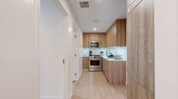 Located at 1427 Barry Ave in the heart of West Los Angeles, this efficiently designed 3-bedroom, 3-bathroom unit offers a thoughtfully laid-out floor plan that maximizes every inch of available space. The interior showcases a consistent modern aesthetic, with warm wood-toned cabinetry, white quartz countertops, and light hardwood flooring that flow cohesively throughout.

The kitchen is a standout feature, outfitted with flat-front wood cabinetry, white countertops, under-cabinet lighting, a white tile backsplash, and stainless steel appliances including a full gas range and over-the-range microwave. Its galley-style layout makes efficient use of the space while maintaining a clean, contemporary look.

Each of the three bathrooms is finished with large-format light grey tile, glass-enclosed walk-in showers with built-in niches, wood vanity cabinetry, and white undermount sinks with mirrored storage above. The design is consistent and polished throughout. The bedrooms are compact yet functional, with built-in Murphy bed-style configurations noted in select rooms to optimize flexibility.

A dedicated laundry area and hallway provide additional convenience. The unit also features a private balcony offering open views of the surrounding West Los Angeles neighborhood. The overall ambiance is clean, modern, and well-organized.