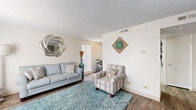 Located at 12185 Albrook Dr in Denver, CO, this one-bedroom, one-bathroom residence offers a thoughtfully organized single-floor layout that makes efficient use of its space. The living room features wood-style flooring, a textured ceiling, and natural light streaming through vertical blinds, creating a bright and comfortable gathering area. An adjacent dining nook, equipped with a ceiling fan and a large window, provides a dedicated space for meals. The galley-style kitchen runs alongside the dining area and includes dark wood cabinetry, white countertops, a double-basin sink, and full-size appliances, with a hallway connecting directly to the bathroom and bedroom beyond. The full bathroom offers a tiled shower-tub combination, wood-style flooring, and open shelving for storage. The carpeted bedroom is a calm retreat with a textured ceiling, a window for natural light, and access to two closets, providing ample storage. A hallway connects the main living areas to the private spaces, adding to the unit's logical flow. Throughout the residence, neutral wall tones and consistent flooring choices create a cohesive and clean aesthetic well-suited for comfortable everyday living in Denver's 80239 neighborhood.