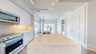 Located in Dallas's vibrant Uptown neighborhood, this modern one-bedroom, one-bathroom residence offers a sophisticated urban living experience. The open-concept layout flows seamlessly from the entrance through a bright, airy living and dining area, anchored by expansive floor-to-ceiling windows that frame sweeping views of the Dallas skyline and surrounding cityscape, flooding the space with natural light.

The contemporary kitchen is a standout feature, showcasing an oversized waterfall quartz island with an undermount sink, sleek white flat-panel cabinetry, stainless steel appliances including a French door refrigerator and microwave, and under-cabinet lighting. Rich hardwood flooring extends throughout the entire residence, adding warmth and contrast to the clean white palette.

The well-proportioned bedroom offers a tranquil retreat with a tray ceiling and direct access to the main living area. The bathroom is finished with large-format wood-grain tiles lining the soaking tub surround, complemented by wood-look tile flooring. Additional conveniences include two closets with adjustable shelving systems, an in-unit laundry area, and a keypad-secured entrance. The overall aesthetic is clean, modern, and move-in ready.