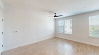 Located at 2403 Mall Dr in North Charleston, SC, this single-floor unit offers a clean, modern aesthetic with thoughtfully designed living spaces. The open-concept kitchen and living area form the heart of the unit, where light wood-tone flooring flows seamlessly throughout, creating a cohesive and airy feel. The kitchen is outfitted with crisp white cabinetry, dark granite-style countertops, a classic subway tile backsplash, and a full suite of stainless steel appliances, including a refrigerator, electric range, and built-in microwave. A central island with a built-in sink and pendant globe lighting above serves as a functional and stylish focal point, ideal for both meal prep and casual dining. The living area benefits from multiple windows fitted with horizontal blinds, allowing natural light to brighten the space, while a ceiling fan provides year-round comfort. The bathroom features a full tub-and-shower combination with built-in shelving, accented by matte black fixtures that contrast cleanly against the all-white surroundings. Light wood flooring and white walls carry throughout, reinforcing a fresh, contemporary atmosphere that makes efficient use of every square foot.