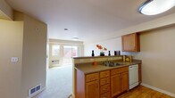 Located at 1706 Fairway Drive in Walla Walla, Washington, Unit 212 is a thoughtfully laid-out single-floor residence that balances functionality with comfortable living. The kitchen is a standout feature, showcasing warm honey-toned wood cabinetry, durable countertops, and a full suite of white appliances including a dishwasher, electric range, and built-in microwave. A peninsula with a double-basin sink connects the kitchen to the living area, creating an open and airy flow between spaces. The flooring transitions seamlessly from hardwood-style planks in the kitchen to plush wall-to-wall carpeting in the living and bedroom areas. The living room benefits from a sliding glass door that opens to a private balcony, allowing natural light to fill the space and providing pleasant outdoor views. The bedroom is generously proportioned, featuring large windows with views of the surrounding neighborhood, soft carpeting underfoot, and baseboard heating for year-round comfort. The bathroom is clean and functional, featuring warm wood cabinetry, a wide countertop vanity, a large mirror, and hardwood-style flooring. The overall color palette throughout the unit is soft and neutral, with warm beige tones creating a welcoming and cohesive ambiance across all rooms.