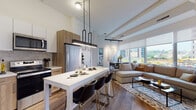 Located at 1 Martine Ave in White Plains, NY, this contemporary single-floor residence showcases a thoughtfully designed open-concept layout that seamlessly connects the kitchen, dining, and living areas. The kitchen is outfitted with stainless steel appliances, two-tone wood and white cabinetry, a tile backsplash, and a large white island with pendant lighting overhead — ideal for both cooking and casual dining. Hardwood flooring flows throughout the main living spaces, adding warmth and continuity to the modern aesthetic. The living room is anchored by floor-to-ceiling windows that flood the space with natural light and offer views of the surrounding White Plains cityscape and outdoor courtyard below. A dedicated dining nook with a marble-top table sits beside expansive windows, enhancing the airy atmosphere. The bedroom is a calm retreat featuring soft neutral tones and ample room for furnishings. A secondary room provides flexibility as a home office or additional bedroom. The bathroom is finished with large-format cream tile, a glass-enclosed shower, and a clean, spa-like design. Throughout, the residence balances contemporary finishes with a welcoming, livable character.