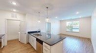 Located at 1200 River Drive in Belmont, NC, this well-appointed two-bedroom, two-bathroom residence offers a thoughtfully designed single-floor layout with a clean, modern aesthetic throughout. The open-concept kitchen and living area serves as the heart of the home, showcasing a large center island with striking dark granite countertops, white shaker-style cabinetry, a white subway tile backsplash, and a full suite of stainless steel appliances including a refrigerator, oven, and built-in microwave. Pendant lighting above the island adds a polished finishing touch. Wood-look flooring runs through the main living areas, lending warmth and continuity to the space. Both bedrooms are well-sized and carpeted, each featuring a ceiling fan and windows that bring in natural light and neighborhood views. The primary bedroom offers a comfortable retreat with dedicated closet space. The two bathrooms are finished with granite-topped vanities, undermount sinks, and tub-shower combinations set on wood-look flooring. Additional highlights include a dedicated laundry area with a stacked washer and dryer unit, two closets for ample storage, and recessed lighting throughout. The overall design is bright, clean, and functional.