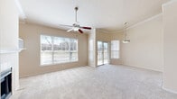 Located at 7101 Chase Oaks Boulevard in Plano, TX, this one-bedroom, one-bathroom residence offers a thoughtfully designed layout across a single floor. The open-concept living and kitchen area is immediately welcoming, highlighted by soaring vaulted ceilings and abundant natural light streaming through large windows and a sliding glass door that leads to a private balcony overlooking the surrounding greenery. A tile-surround fireplace with built-in shelving serves as a standout focal point in the living room, complemented by plush carpeting and a ceiling fan overhead. The kitchen features dark cabinetry, granite-style countertops, a breakfast bar peninsula, stainless steel refrigerator, and a decorative tile backsplash — all set on rich hardwood-style flooring. The spacious bedroom boasts its own vaulted ceiling, ceiling fan, and access to a walk-in closet with built-in shelving. The full bathroom is well-appointed with dark vanity cabinetry, a white countertop, a tub-shower combo with sliding glass doors, and matching hardwood-style floors. Additional conveniences include a dedicated laundry area with washer/dryer hookups and overhead wire shelving, along with a hallway connecting all spaces efficiently.