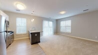 This single-floor residence in Plymouth, Massachusetts, offers a thoughtfully designed open-concept layout that seamlessly connects the kitchen and living areas. The kitchen is outfitted with stainless steel appliances, including a full-size refrigerator, gas range, and built-in microwave, complemented by a combination of white upper cabinetry and dark wood-toned lower cabinets. A peninsula with a granite countertop and pendant lighting above serves as a natural divider between the kitchen and the expansive carpeted living area. Multiple windows and a sliding glass door flood the open living space with natural light, creating a bright and welcoming atmosphere.

The bedrooms are carpeted and well-proportioned, each featuring windows with outdoor views and generous closet space. One bedroom includes a ceiling fan, while walk-in closets fitted with wire shelving systems provide ample storage. Two bathrooms serve the residence: one features a walk-in shower with tile surround, and the other offers a full tub-shower combination. Both bathrooms include granite-topped vanities with taupe cabinetry, large mirrors, and light tile flooring, maintaining a clean, consistent aesthetic throughout the home.