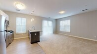 This single-floor residence in Plymouth, Massachusetts, offers a thoughtfully designed open-concept layout that seamlessly connects the kitchen and living areas. The kitchen is outfitted with stainless steel appliances, including a full-size refrigerator, gas range, and built-in microwave, complemented by a combination of white upper cabinetry and dark wood-toned lower cabinets. A peninsula with a granite countertop and pendant lighting above serves as a natural divider between the kitchen and the expansive carpeted living area. Multiple windows and a sliding glass door flood the open living space with natural light, creating a bright and welcoming atmosphere.

The bedrooms are carpeted and well-proportioned, each featuring windows with outdoor views and generous closet space. One bedroom includes a ceiling fan, while walk-in closets fitted with wire shelving systems provide ample storage. Two bathrooms serve the residence: one features a walk-in shower with tile surround, and the other offers a full tub-shower combination. Both bathrooms include granite-topped vanities with taupe cabinetry, large mirrors, and light tile flooring, maintaining a clean, consistent aesthetic throughout the home.
