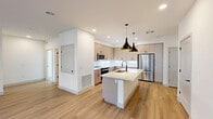 Located at 4900 East Deer Valley Drive in Phoenix, AZ, this single-story, 4-bedroom, 2-bathroom home offers a clean, modern aesthetic throughout. The open-concept layout seamlessly connects the dining room, kitchen, and living room, creating a bright and functional shared space. Light-toned hardwood flooring runs throughout the main living areas, complemented by recessed lighting and ceiling fans that enhance airflow and ambiance.

The contemporary kitchen is a standout feature, boasting a large central island with a striking veined stone countertop, warm taupe flat-front cabinetry with matte black hardware, stainless steel appliances, and dramatic pendant lighting. The space flows naturally into the living area, which includes a window and door leading to a private patio.

The four bedrooms feature plush carpeting and ceiling fans, with windows offering outdoor views. The generously sized primary bedroom includes an expansive walk-in closet with custom built-in shelving and hanging systems. Both bathrooms are finished with large-format tile flooring, light wood vanities, white countertops, and matte black fixtures. A dedicated laundry area and six closets throughout provide abundant storage. The entrance corridor leads cleanly into the heart of the home, reinforcing the cohesive, minimalist design.