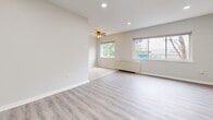 Located at 6451 Oxford Ave in Philadelphia's Fox Chase neighborhood, this well-appointed 1-bedroom, 1-bathroom unit offers a thoughtfully designed single-floor layout. The combined kitchen and living room forms the heart of the home, with the kitchen showcasing warm honey-toned wood cabinetry, a subway tile backsplash, light large-format tile flooring, and stainless steel appliances including a full-size refrigerator and gas range. The adjacent living area transitions to light gray laminate wood flooring and is brightened by multiple windows framing lush greenery views, a ceiling fan, and a baseboard heating unit. Recessed lighting and vaulted ceilings in the living space enhance the sense of openness and airiness throughout. The bedroom is carpeted for comfort, bathed in natural light through a large window with tree views, and includes a baseboard heater for year-round comfort. The full bathroom features clean white finishes, large-format tile flooring, a shower/tub combination with a mosaic tile accent stripe, a dark-stained vanity cabinet, and the added convenience of a stacked in-unit washer and dryer. Neutral tones and clean lines throughout create a cohesive, move-in-ready living environment.
