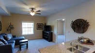 This single-floor residence offers a thoughtfully designed layout that balances comfort and functionality. The living area is a welcoming space finished with plush wall-to-wall carpeting and neutral-toned walls that create a warm, inviting ambiance. A ceiling fan with a built-in light fixture anchors the room, providing both air circulation and ambient lighting. A double-hung window allows natural light to filter in, brightening the space throughout the day. The living area flows naturally toward an adjoining room, connected through a clean, open doorway that hints at additional living or sleeping space beyond.

The kitchen is positioned adjacent to the living area and features granite countertops with a speckled finish, adding a touch of elegance to the space. A stainless steel sink completes the kitchen's practical setup. The open sightlines between the kitchen and living room create a connected, sociable feel that is ideal for everyday living.

Throughout the residence, the design is clean and understated, with white trim, neutral walls, and recessed lighting accents contributing to a cohesive aesthetic. The overall atmosphere is bright, calm, and move-in ready, making it a practical and comfortable place to call home.