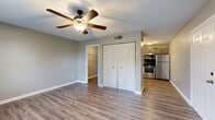 This single-floor residence offers a clean, updated interior with a cohesive design carried throughout. The open living area is finished with wood-look plank flooring, neutral gray-toned walls, and a textured ceiling. A ceiling fan with a light fixture provides both comfort and illumination, while a large window allows natural light to fill the space. A spacious closet with louvered bifold doors adds practical storage.

The kitchen is a standout feature, equipped with gray shaker-style cabinetry, granite countertops, and a classic white subway tile backsplash. A full suite of stainless steel appliances — including a refrigerator, range, over-the-range microwave, and dishwasher — offers modern functionality. The layout is efficient, with ample counter space and cabinetry for storage.

The bathroom continues the refined aesthetic with granite countertops, gray cabinetry with brushed hardware, a large framed mirror, and oil-rubbed bronze accents. An additional room, also featuring a ceiling fan and wood-look flooring, provides flexible use as a bedroom or office, complete with its own closet. The consistent use of neutral tones, updated fixtures, and quality finishes throughout creates a cohesive and move-in-ready living environment.