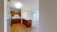 Located at 404 W Smith St in Greensboro, NC, this single-floor, 2-bedroom, 2-bathroom residence offers a thoughtfully designed layout with quality finishes throughout. The open-concept kitchen and living area serves as the heart of the home, featuring rich warm-toned cabinetry, granite countertops, a classic subway tile backsplash, and stainless steel appliances including a range, microwave, and dishwasher. A central kitchen island with pendant lighting adds both functionality and style, flowing seamlessly into the living room. The living room is bathed in natural light thanks to a set of French doors framed by transom windows, accented by crown molding and smooth hardwood-style flooring. The spacious primary bedroom features plush carpeting, a ceiling fan, and a window with outdoor views, complemented by an en-suite bathroom with tile flooring and access to a generous walk-in closet with wire shelving. The second bedroom is equally comfortable with soft carpet and neutral tones. A dedicated laundry room with hardwood-style flooring provides washer and dryer hookups for added convenience. Two closets offer ample storage throughout the home, and a hallway connects all areas for easy navigation.