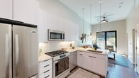 Located at 8555 East Raintree Drive in Scottsdale, Arizona, this thoughtfully designed one-bedroom, one-bathroom residence makes efficient use of its compact footprint through an open-concept layout and soaring ceilings that lend a sense of spaciousness well beyond its physical dimensions. The kitchen is a standout feature, outfitted with full stainless steel appliances including a gas range, built-in microwave, dishwasher, and French door refrigerator. Sleek white flat-front cabinetry with black hardware extends floor to ceiling, complemented by a classic subway tile backsplash and a peninsula with a sink — ideal for both meal prep and casual dining. The kitchen opens directly into the living area, which benefits from large black-framed sliding glass doors that flood the space with natural light and provide access to a private outdoor area with views of the Scottsdale surroundings. The bedroom offers a cozy yet functional retreat, featuring a window, wood-look flooring, and a dedicated workspace area. The bathroom is finished with a walk-in glass-enclosed shower with marble-style tile, a floating white vanity with a neutral countertop, black fixtures, and warm wood-tone flooring. A ceiling fan, smart door lock, and wood-look floors throughout complete this modern, well-appointed Scottsdale residence.