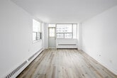 Located on the 21st floor at 45 Dunfield Avenue in Toronto's Midtown neighbourhood, this two-bedroom, one-bathroom unit offers a compact yet efficiently organized layout across a single floor. Light-toned laminate flooring runs throughout the space, lending a cohesive and modern feel to every room.

The spacious primary bedroom is the standout room, featuring large corner windows that flood the space with natural light and frame elevated views of the surrounding Toronto skyline. A baseboard heating unit runs along the exterior wall, ensuring year-round comfort. The second bedroom, while more modest in scale, benefits from its own window with city views and shares the same clean laminate flooring.

The kitchen is neatly appointed with white cabinetry, stone-finish countertops, a subway tile backsplash, and a stainless steel electric range, providing a functional cooking space. A set of louvred doors separates the kitchen from the main living area, which offers an open feel with a direct sightline into the kitchen.

The bathroom features a full soaker tub with an overhead shower, white tile surround, and chrome fixtures, maintaining the unit's clean, neutral aesthetic. A hallway connects all rooms, completing this well-organized urban residence.