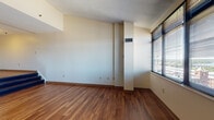 Located at 2 Museum Square in Lawrence, Massachusetts, this single-floor residence offers a thoughtfully designed layout with a variety of functional spaces. The main living area features rich, warm-toned hardwood-style flooring that flows throughout, complemented by neutral wall tones and ample natural light streaming in through large windows fitted with blinds. A raised step detail adds architectural character to the living space.

The kitchen is well-equipped with warm wood cabinetry, granite-style countertops, a stainless steel sink, and black appliances including a full-size refrigerator and dishwasher, all set atop matching hardwood-style flooring.

The bedrooms are carpeted for comfort and feature large windows that frame impressive elevated views of the Lawrence skyline and surrounding cityscape. One bedroom connects directly to a bathroom, offering added privacy. The bathrooms are finished with classic square tile flooring and tub-shower combinations accented with a distinctive turquoise tile border detail, providing a clean and timeless aesthetic.

Throughout the residence, built-in HVAC vents ensure year-round climate control. Multiple closets provide generous storage. The overall ambiance is bright, open, and functional, making this a versatile and comfortable urban residence in the heart of Lawrence.