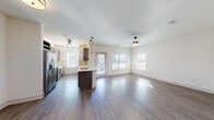 This single-story residence offers a thoughtfully designed open-concept layout that seamlessly connects the kitchen, dining, and living areas. Wood-look flooring flows consistently throughout the space, lending a cohesive and contemporary aesthetic. The kitchen is well-appointed with dark espresso cabinetry, light quartz countertops, a subway tile backsplash, stainless steel appliances including a refrigerator, range, microwave, and dishwasher, and a central island with a sink and pendant lighting overhead. Large windows throughout the unit invite generous natural light into each room, creating a bright and welcoming ambiance.

The living area is spacious and open, featuring a ceiling fan and multiple windows with views to the outdoors. The bedrooms are well-proportioned, each equipped with ceiling fans and sizable windows that bring in natural light. Storage is well-addressed through a generously sized walk-in closet outfitted with multi-tiered wire shelving.

Two bathrooms feature dark vanity cabinetry with white countertops and wood-look tile flooring; one includes a glass-enclosed shower. A dedicated in-unit laundry room accommodates a full-size washer and dryer, adding everyday convenience to this clean, modern space.