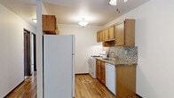 Located in Mequon, Wisconsin, this single-floor, 2-bedroom, 2-bathroom residence offers a well-organized layout designed for comfortable everyday living. The kitchen is efficiently arranged with warm oak cabinetry, granite-style countertops, a mosaic tile backsplash, white appliances including a gas range, dishwasher, and full-size refrigerator, all complemented by light hardwood-style flooring. The living room features rich hardwood flooring and a sliding glass door that floods the space with natural light and provides direct access to a verdant outdoor area with mature shrubs and trees, creating a seamless indoor-outdoor connection. Both bedrooms are bright and carpeted, each with windows dressed in blinds that allow natural light while maintaining privacy. The primary bedroom offers a comfortable footprint, while the second bedroom provides additional flexibility. The two bathrooms are finished consistently with oak vanities, speckled composite countertops, framed mirrors, and brushed nickel hardware. One bathroom includes a full tub-shower combination with built-in shelving. A dedicated closet rounds out the functional layout. The neutral color palette and classic finishes throughout lend the space a clean, timeless character well-suited to Mequon's residential setting.