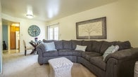 Located at 3900 Woodbridge Drive in Newport News, Virginia, this two-floor home offers a well-designed layout with a variety of functional and comfortable spaces throughout. The living area is generously sized, featuring plush carpeting, soft neutral walls, and a set of French doors that open to a private outdoor patio, allowing natural light to flow into the room. A dedicated dining area sits adjacent, creating a seamless connection between living and entertaining spaces. The kitchen is equipped with warm wood cabinetry, white appliances including a refrigerator, dishwasher, and electric range, along with a peninsula that provides additional counter space and a window that brightens the room. Multiple bedrooms are spread across both floors, each carpeted and featuring natural light from windows with blinds. The upper-floor primary bedroom is notably spacious with vaulted ceilings, a walk-in closet with an en-suite bathroom access, and ample room for a king-sized bed. A secondary bedroom includes a closet and natural light from a well-positioned window. The bathrooms feature wood vanity cabinetry with light countertops and a shower-tub combination. Overall, the home presents a comfortable, practical layout suited for everyday living.