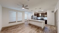 Located in Tomball, TX, this well-appointed one-bedroom, one-bathroom home offers a thoughtfully designed layout with modern finishes throughout. The open-concept living and kitchen area is anchored by a large center island topped with granite countertops, complemented by dark espresso cabinetry, a white subway tile backsplash, stainless steel appliances, and elegant pendant lighting. Wood-look flooring runs throughout the main living areas, while a ceiling fan adds both style and comfort. Natural light filters in through multiple windows fitted with blinds, creating a bright and welcoming atmosphere. The kitchen flows seamlessly into the living area, making the space feel open and functional. The bedroom offers plush carpeting, a ceiling fan, and a window that brings in natural light, providing a comfortable retreat. The full bathroom is well-equipped with a dual-sink vanity featuring granite countertops, dark cabinetry, a soaking tub with subway tile surround, and direct access to a dedicated walk-in closet with built-in shelving. A separate laundry area houses a full-size washer and dryer with overhead shelving for added storage. Every detail of this home reflects a clean, contemporary aesthetic designed for everyday convenience.