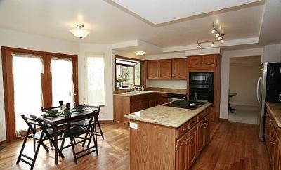 Isla de cocina con placa de cocción, horno empotrado, microondas, ventanal, zona de comedor, despensa, mucho espacio de almacenamiento y suelos de madera. - 6782 Swadley Court