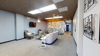 Located at 510 Main St in East Haven, Connecticut, this single-floor amenity space offers a comprehensive range of shared facilities spread across a generously sized floor plan. The layout is thoughtfully organized, connecting its various functional areas through two hallways that guide residents seamlessly from one space to the next.

The exercise room is a standout feature, boasting bold cobalt blue brick walls, durable rubber flooring, and high ceilings equipped with ceiling fans for ventilation. It is outfitted with a full suite of cardio machines, including treadmills and stationary bikes, as well as free weights and strength equipment, making it a well-rounded fitness facility.

The lounge area offers a welcoming atmosphere with neutral grey carpeting, recessed and pendant lighting, and a vibrant abstract mural wall that adds a creative focal point. Comfortable seating arrangements and a wall-mounted television make it an ideal space for relaxation or socializing.

The laundry room is efficiently designed with rows of full-sized washing machines and dryers lining both walls, bright overhead lighting, and easy-to-clean flooring, providing ample capacity for residents.

A kitchenette features dark cabinetry, a stainless steel refrigerator, a microwave, and a sink set over warm wood-look flooring. A dedicated package room with built-in shelving rounds out the amenities, offering organized storage for deliveries.
