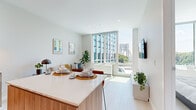 Located at 2100 N Central Rd in Fort Lee, NJ, this thoughtfully designed one-bedroom, one-bathroom residence offers a clean, contemporary aesthetic throughout. The open-plan kitchen and living area serves as the heart of the home, anchored by a sleek island with a white quartz countertop and warm wood cabinetry. Floor-to-ceiling windows flood the space with abundant natural light while framing striking views of the George Washington Bridge and surrounding skyline — a true standout feature of the living area. Light hardwood flooring runs throughout, enhancing the bright and airy atmosphere. The living space is well-proportioned, providing comfortable room for both dining and relaxation. The bedroom is a serene retreat, benefiting from its own large window with continued bridge and greenery views, a double closet, and light neutral tones that promote a restful ambiance. A dedicated office area adds functional versatility to the layout. The full bathroom features large-format tile flooring, a glass-enclosed shower, and clean, modern finishes. A hallway connects the rooms with ease. Overall, this residence combines modern design, smart use of space, and remarkable views into a cohesive and livable home.