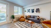 Located at 917 SW 31st St in Battle Ground, WA, this well-designed two-bedroom, one-bathroom apartment offers a thoughtfully arranged single-level floor plan. The open-concept living and kitchen area serves as the heart of the home, with light hardwood-style flooring flowing throughout. The kitchen is a standout feature, boasting rich walnut-toned cabinetry, white quartz countertops, stainless steel appliances including a refrigerator, range, microwave, and dishwasher, and a spacious island with seating — ideal for casual dining or entertaining. The living room is bright and welcoming, featuring a large window that invites natural light and views of surrounding greenery. Both bedrooms are comfortably sized, each with ceiling fans, large windows, and closet storage. The primary bedroom offers a calm, neutral palette with ample natural light. The bathroom continues the modern aesthetic with warm wood cabinetry, a white countertop vanity, and light hardwood-style flooring. Clean lines, recessed lighting, and a consistent neutral color palette give the entire space a cohesive, contemporary feel throughout.