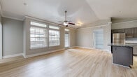 This single-floor residence offers a thoughtfully designed open-concept layout that seamlessly connects the living area and kitchen. The expansive living space features light hardwood-style flooring, vaulted ceilings with a ceiling fan, crown molding, and large windows with transom panels that flood the room with natural light. A glass-paned exterior door provides convenient outdoor access. Built-in shelving adds functional storage and architectural interest.

The kitchen is a standout feature, equipped with gray raised-panel cabinetry, granite countertops, a white subway tile backsplash, stainless steel appliances, and a central island that enhances both workspace and flow. The kitchen connects naturally to the main living area, making it ideal for everyday use and entertaining.

The bedrooms are carpeted for comfort and include ceiling fans and closets with ample storage. Both bathrooms are finished with granite countertops, gray cabinetry, light wood-style tile flooring, and tub-shower combinations with neutral tile surrounds. The primary bathroom features an extended vanity with a large mirror.

A dedicated laundry area accommodates a full-size washer and dryer with built-in shelving above. Neutral warm-toned walls throughout the home contribute to a cohesive, move-in-ready aesthetic.