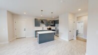 Located at 888 Horizon Boulevard in Athens, GA, this well-appointed 2-bedroom, 2-bathroom single-floor residence offers a thoughtfully designed open-concept layout with modern finishes throughout. The combined kitchen and living area serves as the heart of the home, featuring striking slate-blue cabinetry, white quartz countertops, a subway tile backsplash, stainless steel appliances, and a central island with pendant lighting accented by brass hardware. Marble-look tile flooring flows through the kitchen, while light hardwood flooring extends into the living area, which is finished with recessed lighting and a ceiling fan. A glass-panel door in the living space leads to an outdoor deck with a wooded view beyond. The primary bedroom is a comfortable retreat with dual windows inviting natural light, and both bedrooms are served by dedicated walk-in closets with wire shelving systems. A standout feature is one bedroom's shiplap accent wall, adding a modern farmhouse touch. The two bathrooms are finished with coordinating slate-blue vanities, white quartz counters, marble-look tile flooring, and subway-tiled tub-and-shower surrounds with matte black fixtures. Clean white walls and consistent finishes create a cohesive, contemporary ambiance throughout.