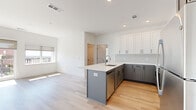 Located at 111 Green St SE in Gainesville, Georgia, this single-floor residence showcases a clean, contemporary design with thoughtfully selected finishes throughout. The open-concept kitchen is a standout feature, boasting two-tone cabinetry — crisp white upper cabinets paired with slate gray lower cabinets — complemented by light quartz countertops, a subway tile backsplash, stainless steel appliances, and a peninsula island with an undermount sink. Light wood-toned flooring runs seamlessly throughout the space, enhancing the bright, airy ambiance created by recessed lighting and abundant natural light. The living area is generously proportioned, with large windows and a sliding glass door that open onto a private balcony offering views of the surrounding Gainesville cityscape. The bathroom features a marble-tiled glass-enclosed walk-in shower, a window with outdoor views, and a refined vanity with quartz counters. Additional highlights include a spacious walk-in closet with built-in shelving and a dedicated in-unit laundry area with a stacked washer and dryer. The overall aesthetic is modern and move-in ready, combining functional design with upscale finishes in a well-connected urban location.