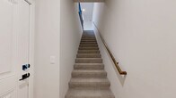 Located in Omaha, Nebraska, this well-appointed 1-bedroom, 1-bathroom two-story residence offers a thoughtfully designed layout spread across two levels. The main living floor showcases an open-concept kitchen and living room finished with warm light hardwood flooring throughout. The kitchen is a standout feature, equipped with stainless steel appliances including a refrigerator, gas range, and built-in microwave, complemented by rich wood shaker cabinetry with matte black hardware and crisp white countertops. A peninsula with an undermount sink and pendant lighting adds both function and style. The living area flows seamlessly to a private balcony through sliding glass doors, offering pleasant outdoor views of surrounding greenery. A tile-surround fireplace anchors the living space, adding warmth and character. The bedroom is carpeted for comfort, features a ceiling fan, and includes a large window for natural light, along with access to a dedicated closet. The full bathroom is finished with light hardwood-style flooring, a wood vanity with matte black fixtures, and a full tub-shower combination. A conveniently located in-unit laundry room with a top-load washer and dryer completes the home's practical offerings.