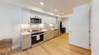 Located at 1765 22nd Ave S in Seattle's Judkins Park neighborhood, this thoughtfully designed one-bedroom, one-bathroom residence makes efficient use of its cozy footprint across a single floor. The open-concept layout connects the kitchen and living areas seamlessly, maximizing functionality throughout.

The kitchen is a standout feature, showcasing a contemporary design with two-tone cabinetry — light wood lower cabinets paired with crisp white upper cabinets — complemented by a subway tile backsplash, quartz countertops, and stainless steel appliances including a range, over-the-range microwave, dishwasher, and refrigerator. Light hardwood flooring runs throughout, lending warmth and continuity to the space.

The bedroom offers a comfortable and well-lit retreat, benefiting from two large floor-to-ceiling windows that flood the room with natural light and provide views of the surrounding neighborhood. The light, neutral palette enhances the sense of openness.

The bathroom features a clean, modern aesthetic with light wood vanity cabinetry, a full-size soaking tub with shower, and neutral tiling. Recessed lighting and chrome fixtures complete the polished look. Overall, the unit delivers a modern, move-in-ready living experience in a well-connected Seattle location.