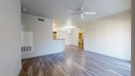This single-floor residence offers a thoughtfully designed layout that balances open communal spaces with comfortable private quarters. The main living area features wood-look plank flooring and vaulted ceilings accented by a ceiling fan, creating an airy and spacious feel. A peninsula-style kitchen counter with granite-look surfaces separates the living space from the galley kitchen, which is equipped with dark appliances, gray cabinetry, and matching countertops. A sliding glass door in the living area fills the space with natural light and provides direct access to an outdoor area. The bedrooms are finished with plush carpeting, ceiling fans, and generous wall space, with natural light filtering in through window treatments. The bathrooms are well-appointed, featuring granite-look vanity countertops, wood-framed mirrors, white cabinetry, and full tub-shower combinations. Wood-look flooring continues through the bathroom spaces, maintaining a cohesive aesthetic throughout. The overall design presents a clean, neutral palette with crisp white walls and modern finishes, making the space feel bright, move-in ready, and versatile for a variety of living arrangements.