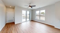 This 670-square-foot second-floor apartment at 305 W Wolf River Avenue in New London offers a well-designed single-level layout that efficiently combines functionality and modern finishes. The open-concept kitchen and living area forms the heart of the unit, where light wood-toned laminate flooring flows throughout, creating a cohesive and bright atmosphere.

The kitchen is equipped with light maple cabinetry featuring matte black hardware, stainless steel appliances including a refrigerator, electric range, and microwave, and a white subway tile backsplash. A peninsula with a gray countertop provides additional workspace and casual seating. In-unit washer and dryer hookups are accessible via a closeted alcove off the kitchen corridor, adding notable convenience.

The living area is generously lit by large windows and a sliding glass door that opens onto a private balcony with metal railing, offering outdoor views of the surrounding streetscape. A ceiling fan with integrated lighting serves the living space. The bathroom features a full-size soaking tub and shower combination with clean white surrounds and chrome fixtures. The unit's neutral color palette and contemporary finishes contribute to a clean, move-in-ready aesthetic throughout.